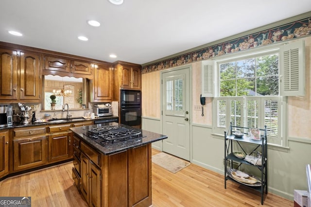 681 Hampton Pl SW, Marietta, GA 30064 - kitchen featuring a kitchen island, dark stone countertops, a sink, light wood-style flooring, and black appliances