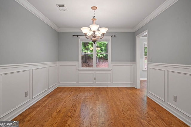 5755 Hendrix Rd, Cumming, GA 30040 - unfurnished dining area featuring a chandelier, light wood finished floors, ornamental molding, wainscoting, and a decorative wall