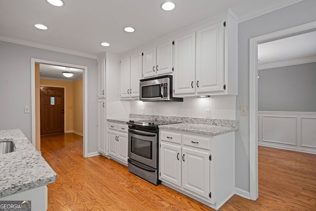 5755 Hendrix Rd, Cumming, GA 30040 - kitchen featuring appliances with stainless steel finishes, white cabinets, light wood-style flooring, crown molding, and light stone counters