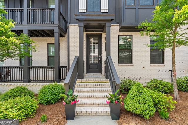 entrance to property with brick siding, board and batten siding, and a balcony