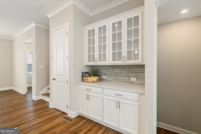 bar featuring crown molding, dark wood-style flooring, baseboards, tasteful backsplash, and visible vents