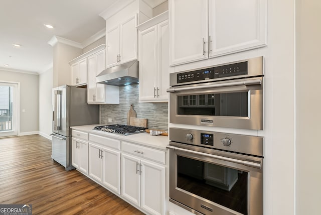 kitchen with crown molding, white cabinets, appliances with stainless steel finishes, backsplash, and under cabinet range hood
