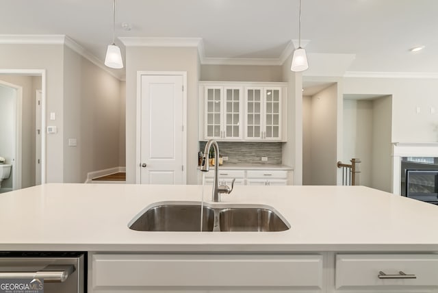 kitchen with light countertops, stainless steel dishwasher, decorative light fixtures, and a sink