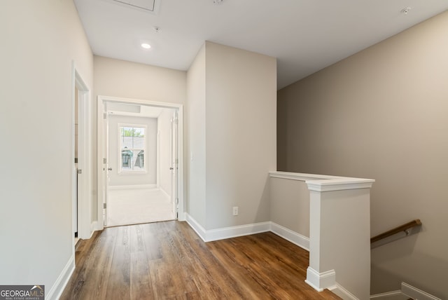 corridor with baseboards, recessed lighting, wood finished floors, and an upstairs landing