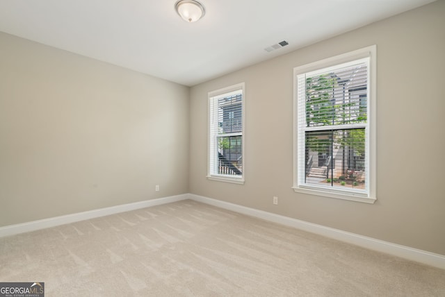 spare room with light colored carpet, baseboards, and visible vents