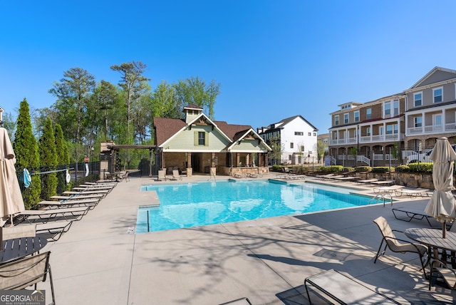 community pool with a patio, fence, and a residential view