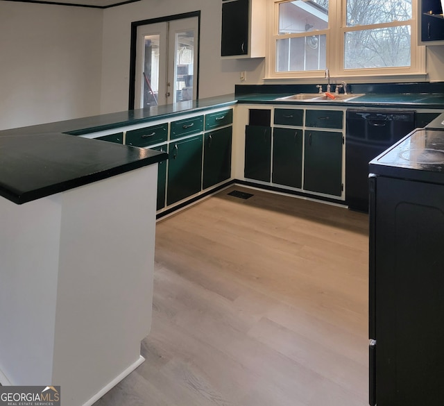 kitchen featuring a sink, dark countertops, a peninsula, and light wood-type flooring