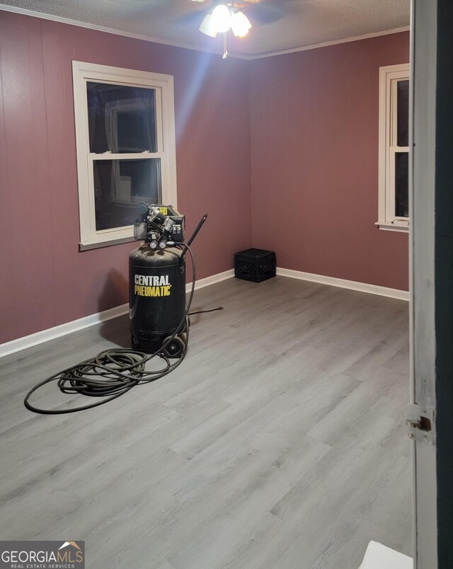 unfurnished room featuring baseboards, ceiling fan, ornamental molding, and wood finished floors
