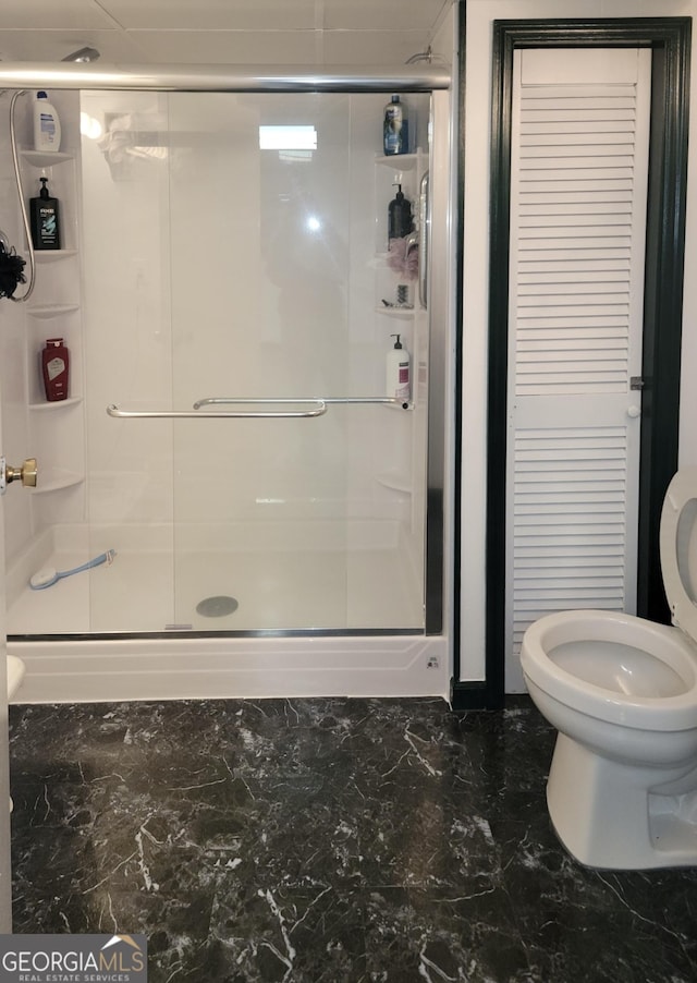 bathroom with marble finish floor, toilet, and a shower stall