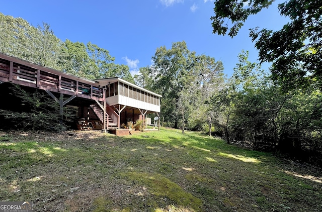 view of yard with a deck, a sunroom, and stairway
