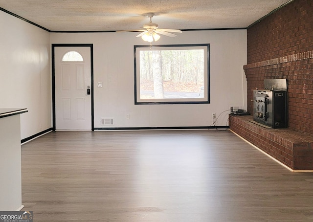 unfurnished living room with a fireplace, a ceiling fan, wood finished floors, and a wealth of natural light