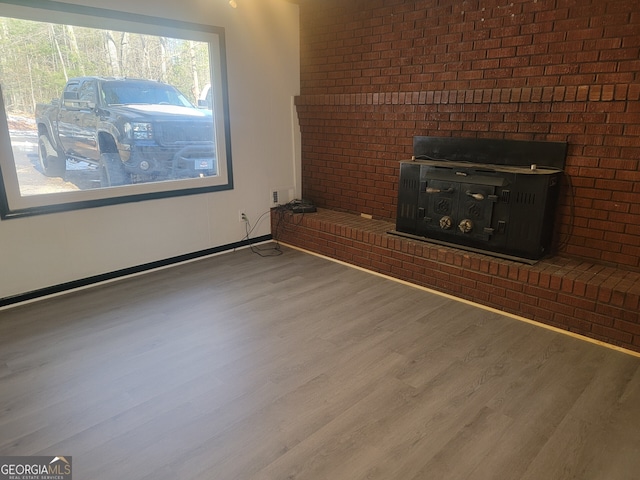 unfurnished living room featuring brick wall and wood finished floors
