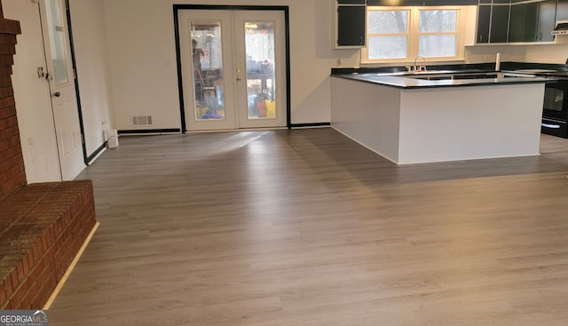 kitchen with electric range, a peninsula, wood finished floors, and dark countertops