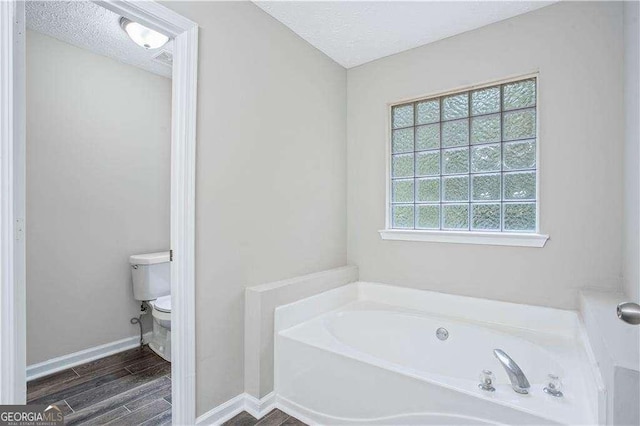 4872 Lewis Rd, Powder Springs, GA 30127 - full bathroom with a textured ceiling, a bath, wood finished floors, baseboards, and toilet
