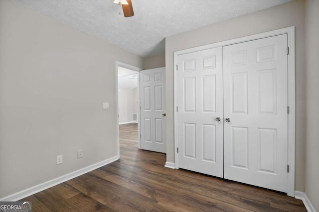 unfurnished bedroom with a closet, baseboards, ceiling fan, a textured ceiling, and dark wood finished floors