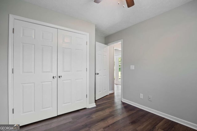 unfurnished bedroom with dark wood-style flooring, ceiling fan, a textured ceiling, baseboards, and a closet