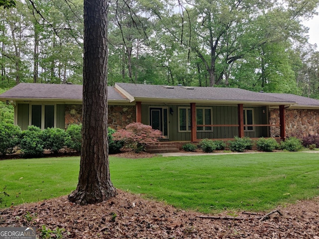 ranch-style home featuring covered porch, board and batten siding, a front lawn, and stone siding