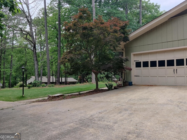 view of property exterior featuring a lawn, an attached garage, and driveway