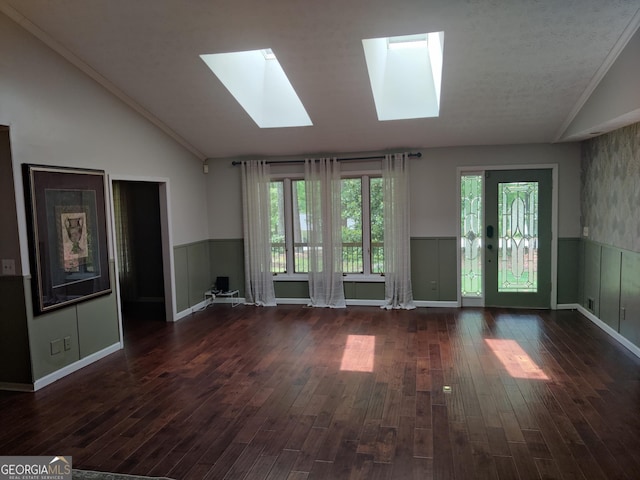 unfurnished living room featuring wood finished floors, lofted ceiling with skylight, and a wainscoted wall