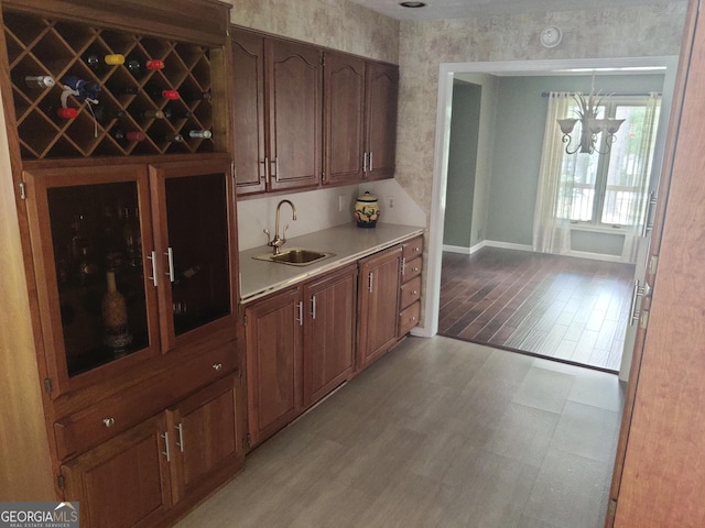 bar with baseboards, a sink, and light wood finished floors