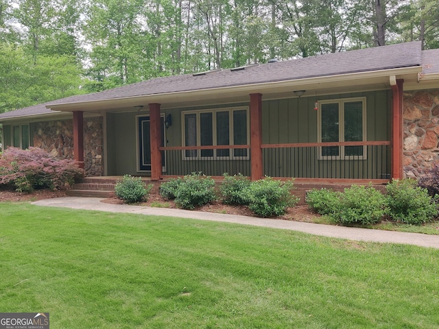 view of front of house featuring a front yard, a porch, and stone siding