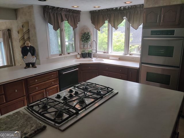 kitchen with stainless steel double oven, a sink, dishwashing machine, recessed lighting, and white gas stovetop
