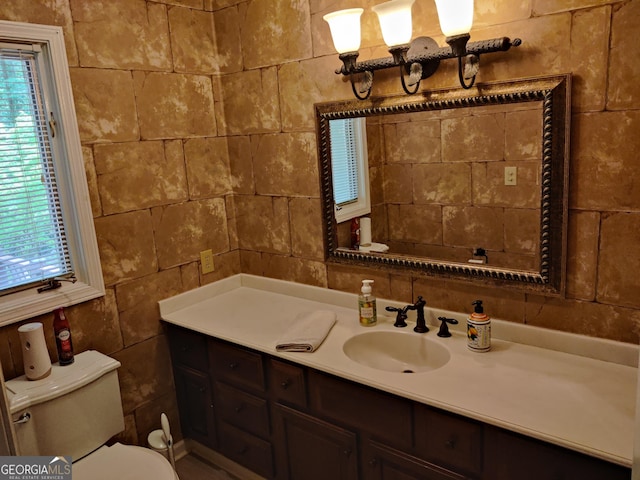 bathroom with vanity, toilet, and tile walls