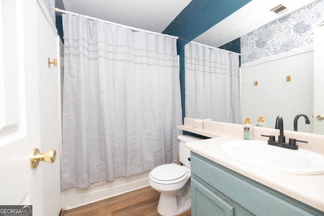 bathroom with visible vents, vanity, wood finished floors, toilet, and shower / bathtub combination with curtain