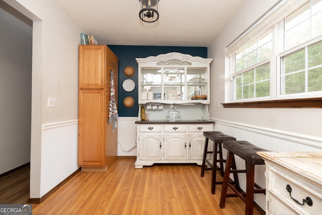 bar featuring light wood-style floors and tasteful backsplash