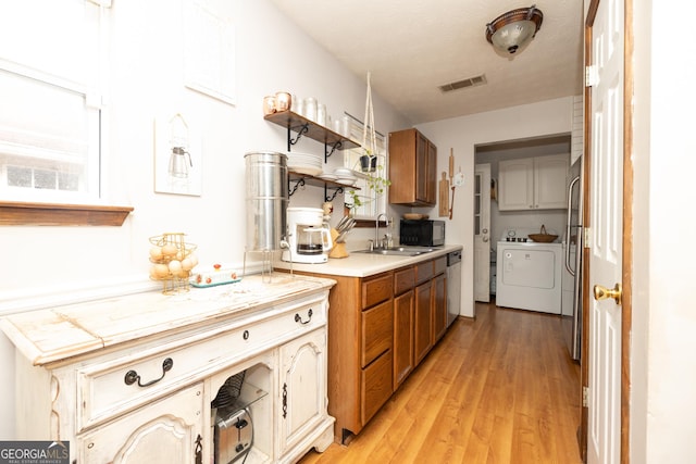 kitchen featuring brown cabinetry, visible vents, light countertops, a sink, and stainless steel appliances