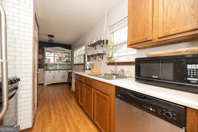 kitchen with black microwave, light wood-style floors, light countertops, a sink, and dishwasher