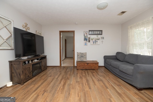 living room with baseboards, light wood-type flooring, and visible vents