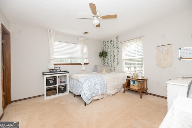 bedroom with multiple windows, a ceiling fan, visible vents, and light colored carpet