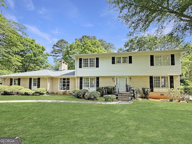 view of front of property featuring a chimney, a front yard, and brick siding