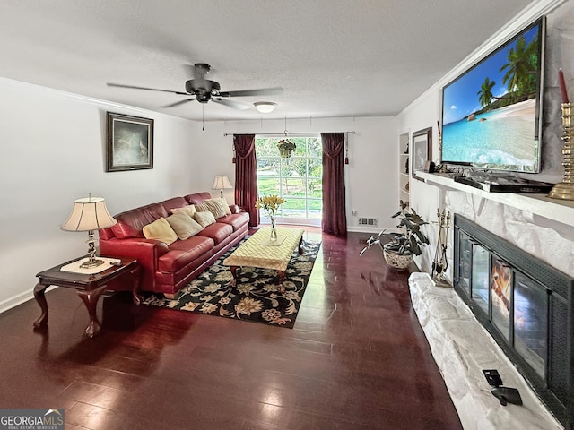 living area with visible vents, wood finished floors, baseboards, a high end fireplace, and a ceiling fan