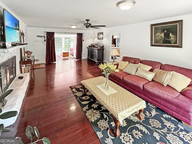 living room featuring a ceiling fan, visible vents, crown molding, wood finished floors, and a glass covered fireplace