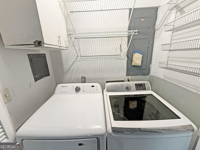 clothes washing area featuring separate washer and dryer, electric panel, and cabinet space