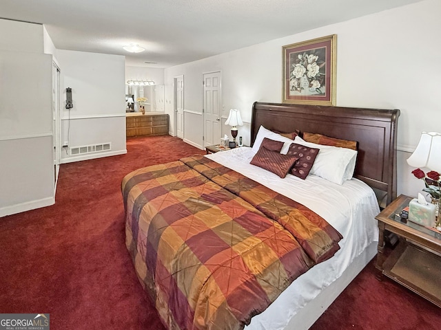 carpeted bedroom featuring visible vents, baseboards, and ensuite bathroom