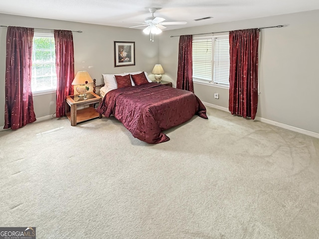 carpeted bedroom with baseboards, a ceiling fan, and visible vents