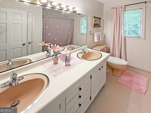bathroom featuring a sink, toilet, and double vanity