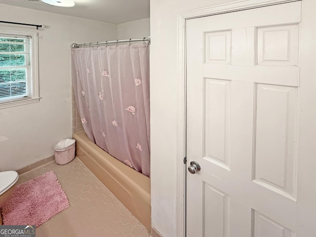 full bath with tile patterned floors, shower / bath combo, and toilet