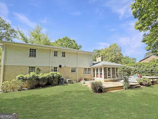 back of property with a sunroom, a lawn, and brick siding
