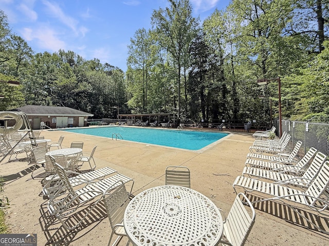 pool with fence, outdoor dining space, and a patio area