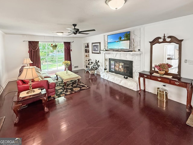 living room with a ceiling fan, a fireplace, wood finished floors, baseboards, and ornamental molding