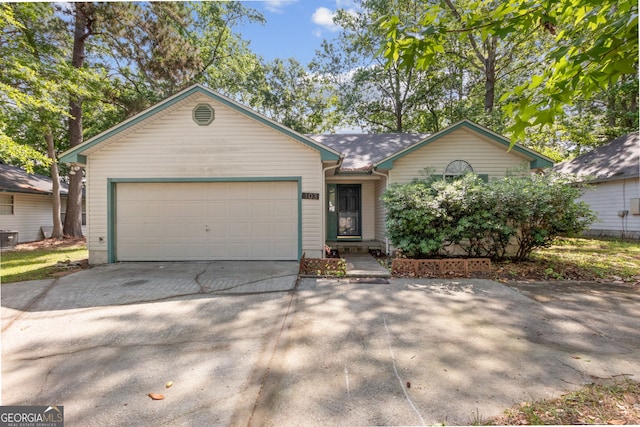ranch-style home featuring central air condition unit, driveway, and a garage