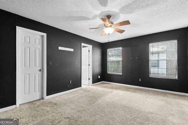 unfurnished room with carpet floors, a textured ceiling, baseboards, and ceiling fan