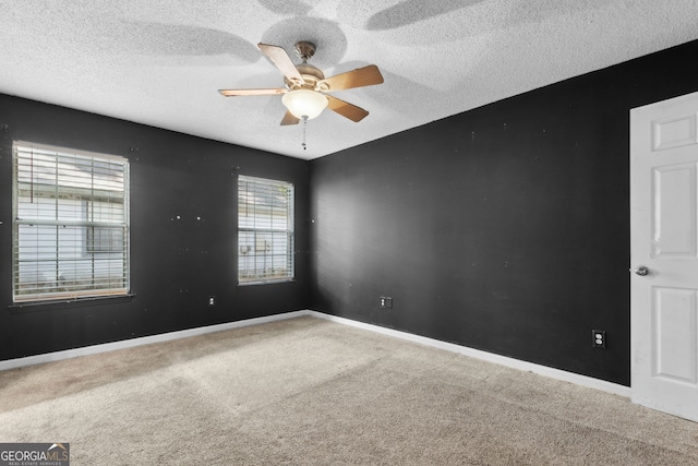 carpeted empty room featuring a textured ceiling, ceiling fan, and baseboards