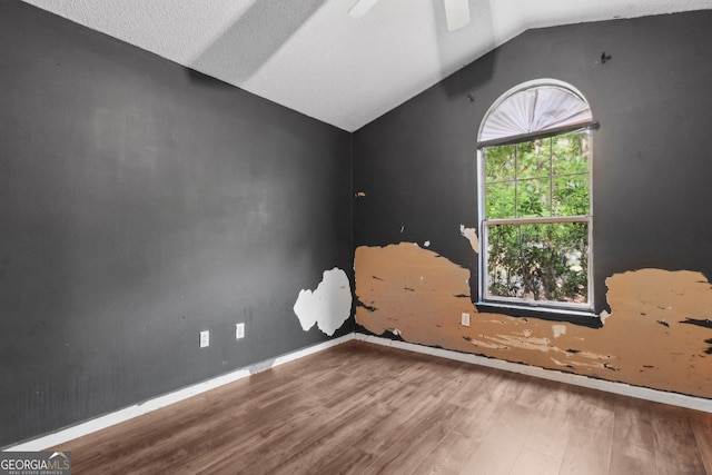 empty room featuring baseboards, ceiling fan, vaulted ceiling, and wood finished floors
