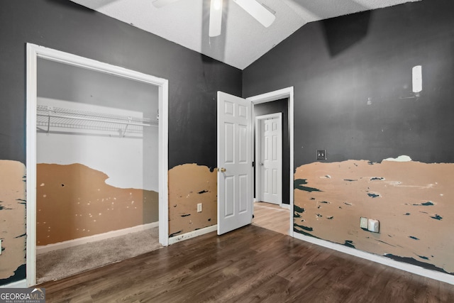 unfurnished bedroom featuring a ceiling fan, a closet, wood finished floors, and lofted ceiling