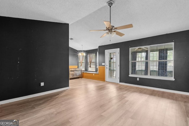 unfurnished living room featuring a healthy amount of sunlight, wood finished floors, a textured ceiling, and lofted ceiling